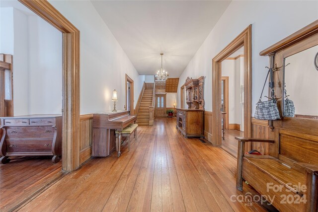 hall with wood walls, a chandelier, and light wood-type flooring