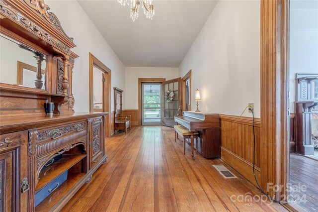 hall featuring hardwood / wood-style flooring, a chandelier, and wooden walls