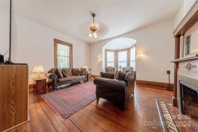 living room with ceiling fan, a fireplace, plenty of natural light, and dark hardwood / wood-style floors