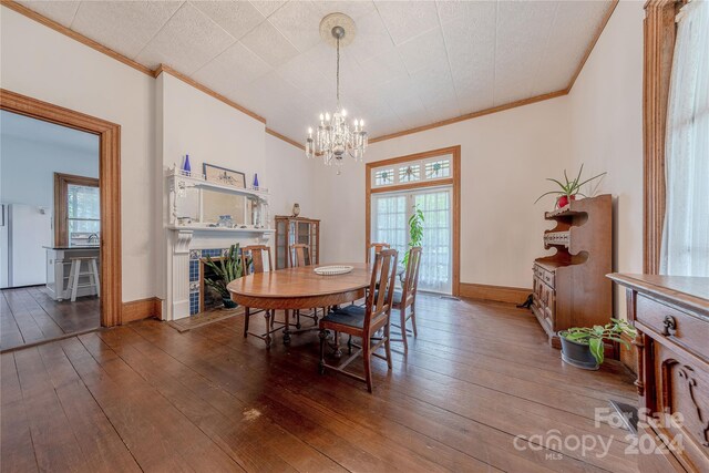 dining area with ornamental molding, a tile fireplace, plenty of natural light, and hardwood / wood-style floors