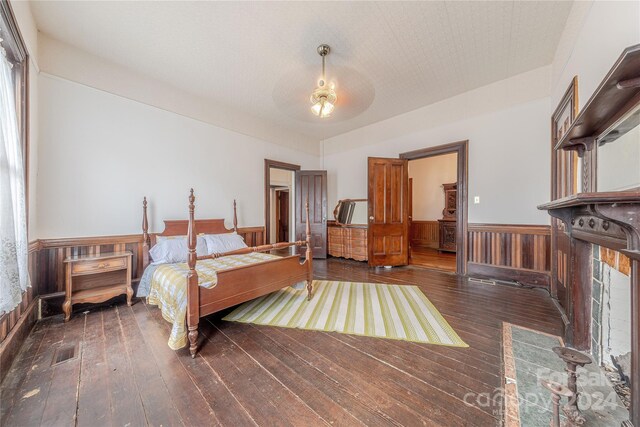 bedroom featuring wooden walls and dark hardwood / wood-style floors