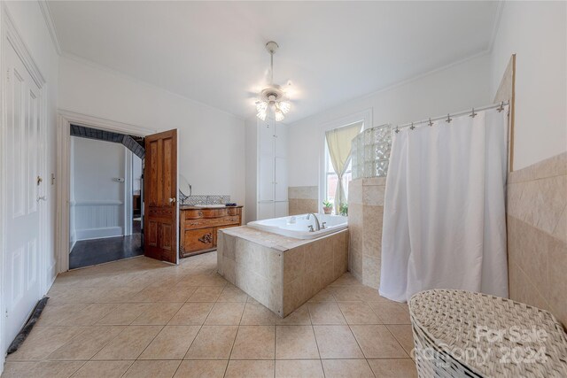 bathroom featuring ceiling fan, tiled tub, vanity, crown molding, and tile patterned flooring