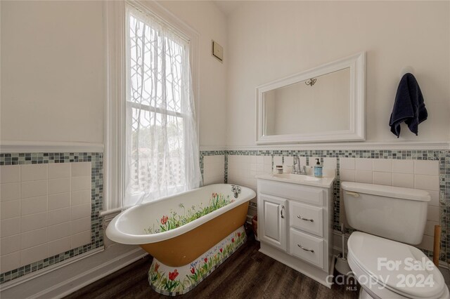 bathroom with hardwood / wood-style flooring, tile walls, toilet, a washtub, and vanity