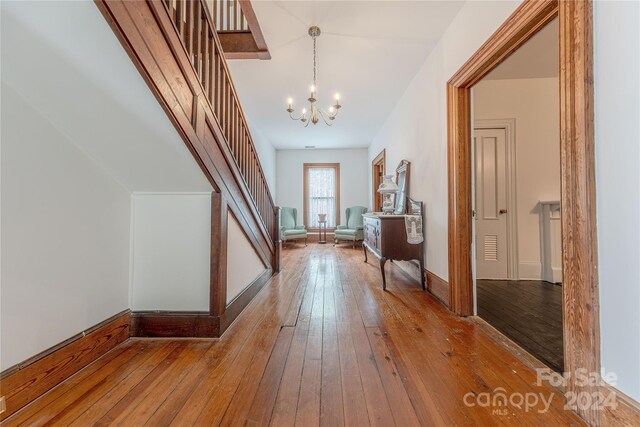 corridor with hardwood / wood-style flooring and a chandelier