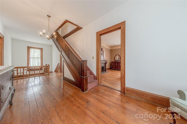 staircase with hardwood / wood-style floors and a chandelier