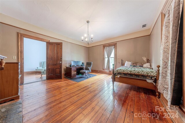 bedroom featuring a notable chandelier, a textured ceiling, and hardwood / wood-style floors