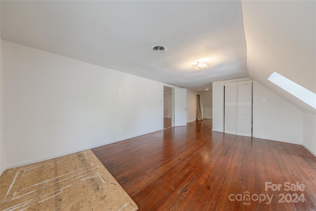 bonus room featuring vaulted ceiling with skylight and dark hardwood / wood-style flooring