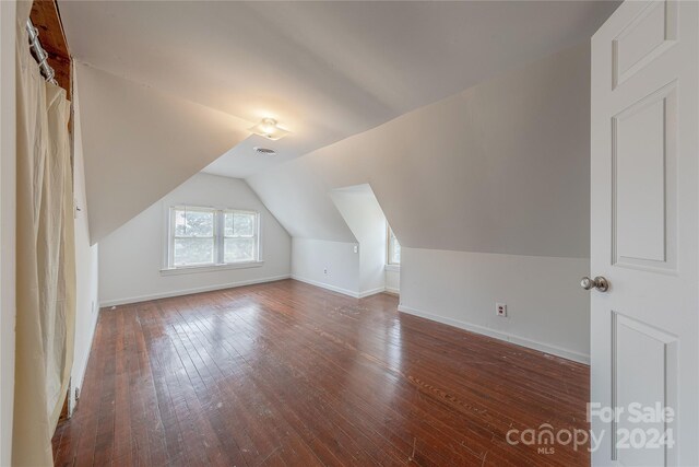 additional living space featuring vaulted ceiling and dark hardwood / wood-style flooring