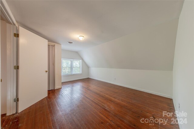 additional living space with vaulted ceiling and dark hardwood / wood-style floors