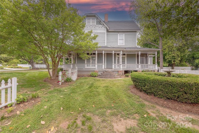 victorian-style house featuring a wooden deck and a lawn