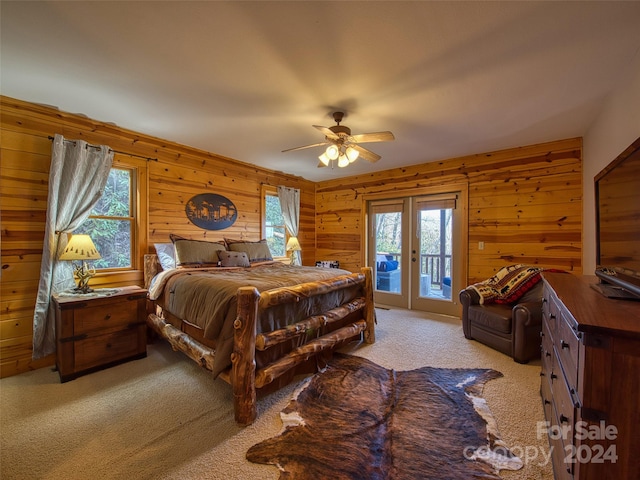 bedroom featuring wood walls, ceiling fan, light carpet, and access to exterior