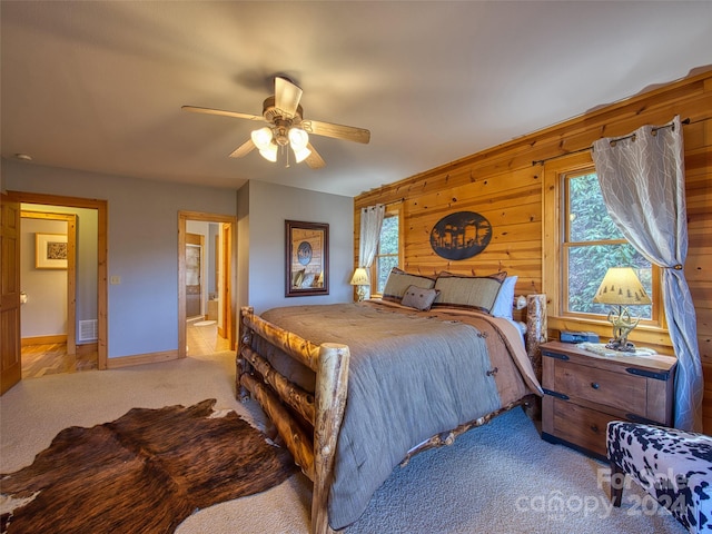 bedroom with ensuite bathroom, light carpet, ceiling fan, and multiple windows