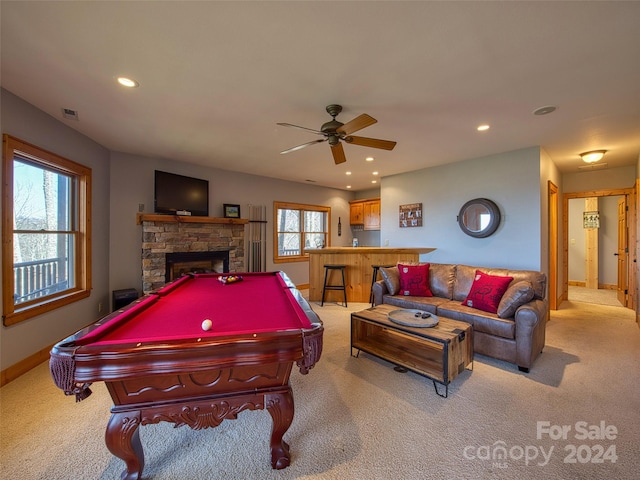 rec room featuring a stone fireplace, pool table, light carpet, and ceiling fan