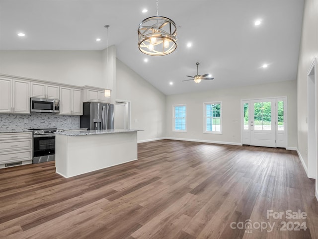 kitchen with ceiling fan with notable chandelier, pendant lighting, appliances with stainless steel finishes, backsplash, and high vaulted ceiling