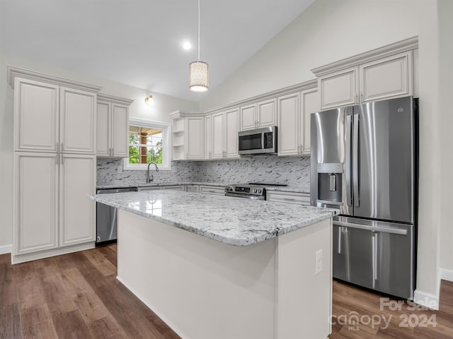 kitchen featuring tasteful backsplash, appliances with stainless steel finishes, lofted ceiling, and a kitchen island