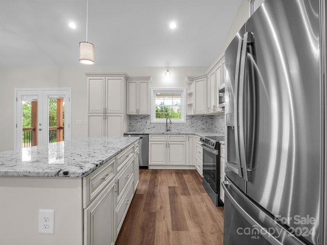 kitchen featuring stainless steel appliances, tasteful backsplash, a center island, decorative light fixtures, and sink