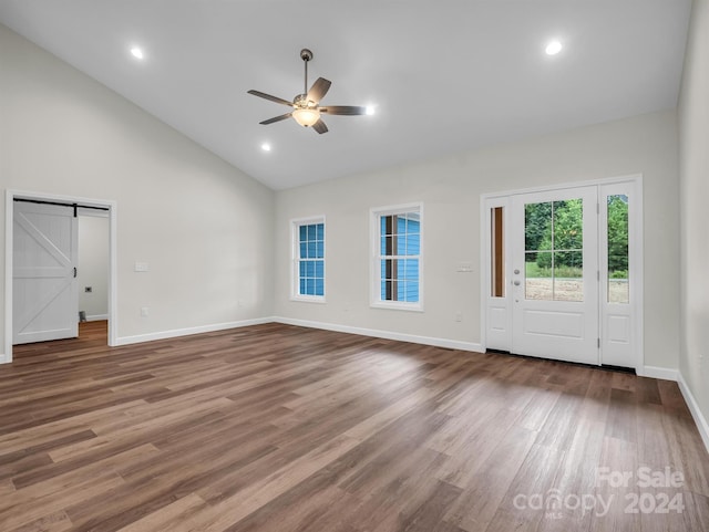 unfurnished living room with ceiling fan, hardwood / wood-style floors, and a barn door