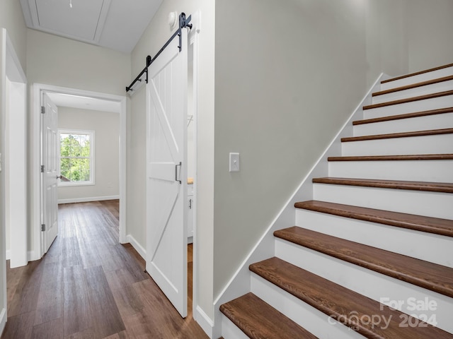 staircase with a barn door and hardwood / wood-style floors