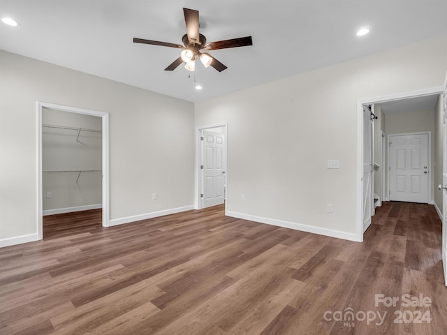 unfurnished bedroom with ceiling fan, wood-type flooring, a closet, and a walk in closet