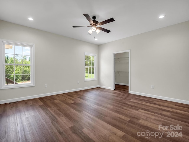 interior space featuring ceiling fan, multiple windows, a spacious closet, and dark hardwood / wood-style flooring