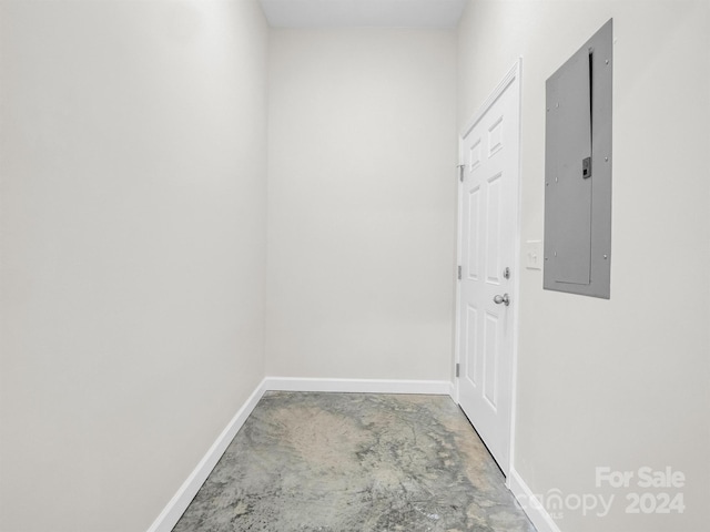 doorway to outside featuring electric panel and concrete flooring