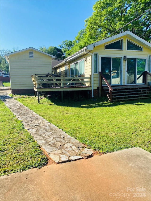 rear view of property featuring a wooden deck and a lawn