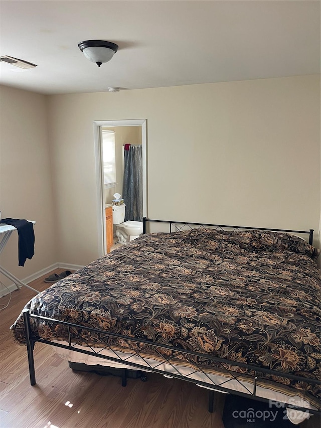 bedroom featuring connected bathroom and light hardwood / wood-style flooring