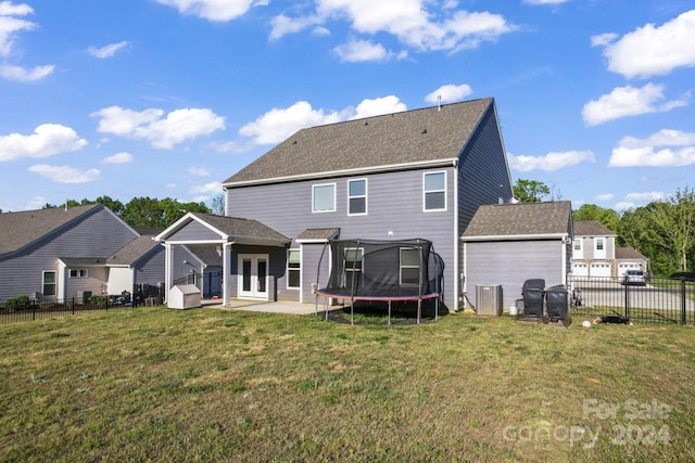 rear view of property featuring a patio, a trampoline, and a yard