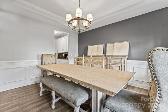 dining area featuring a chandelier, hardwood / wood-style flooring, and a tray ceiling