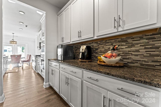 kitchen with white cabinets, hardwood / wood-style floors, tasteful backsplash, and dark stone countertops