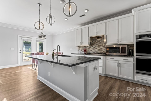 kitchen featuring pendant lighting, appliances with stainless steel finishes, dark hardwood / wood-style flooring, and a center island with sink