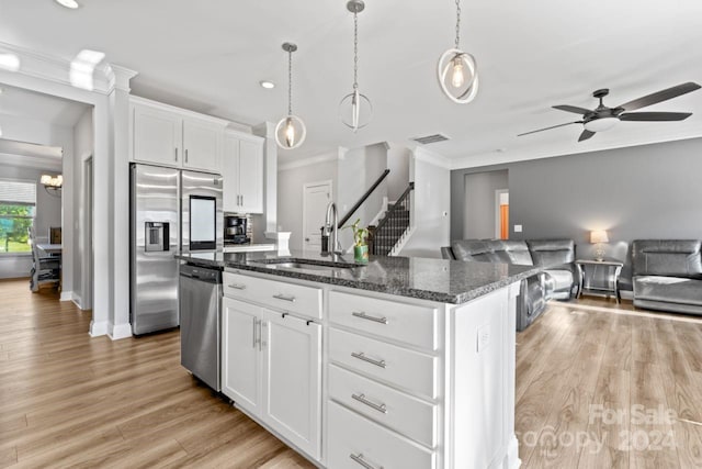 kitchen featuring sink, a center island with sink, light wood-type flooring, and pendant lighting