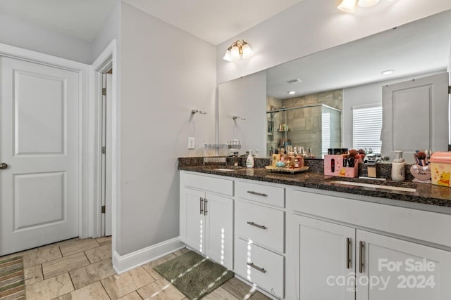 bathroom with tile flooring, a shower with door, large vanity, and double sink