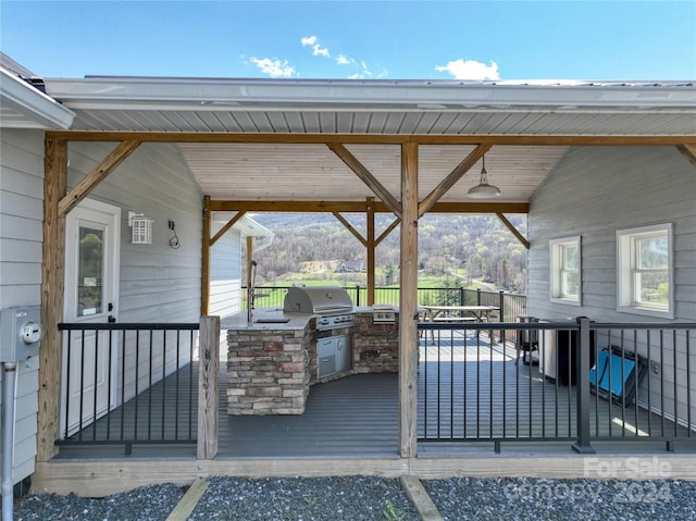 wooden terrace with area for grilling, a mountain view, and an outdoor kitchen