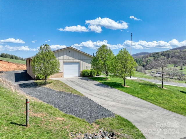 single story home with a mountain view, a garage, and a front lawn