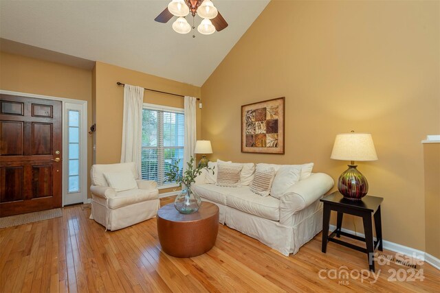 living room with high vaulted ceiling, ceiling fan, and light wood-type flooring