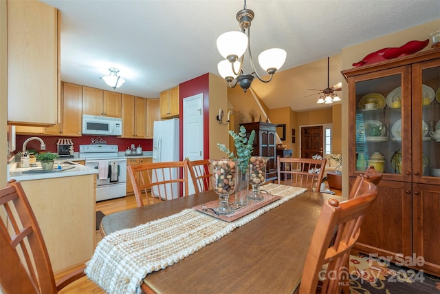 dining space with ceiling fan with notable chandelier, sink, and light wood-type flooring