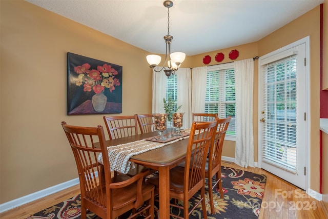 dining space featuring hardwood / wood-style flooring, a healthy amount of sunlight, and a chandelier