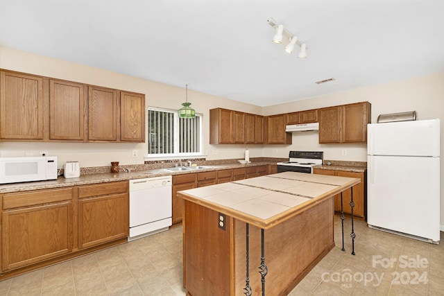 kitchen featuring rail lighting, white appliances, a center island, and light tile floors