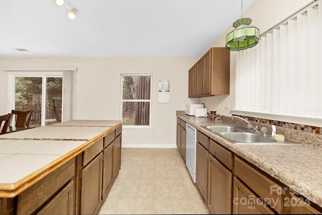 kitchen with hanging light fixtures, sink, dishwasher, and light tile floors