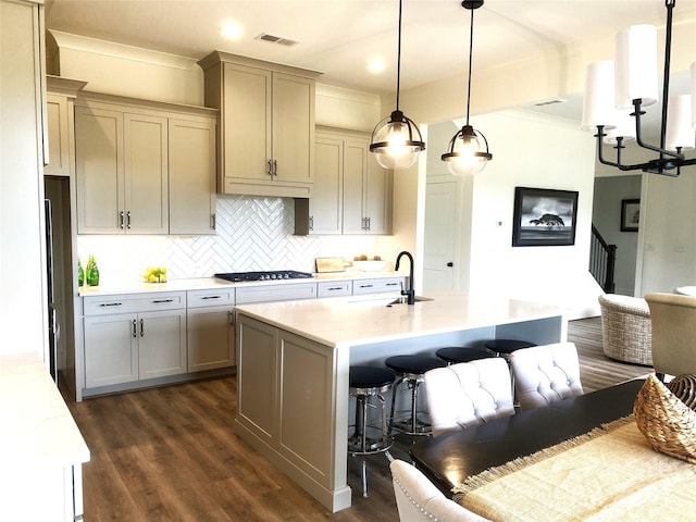 kitchen featuring decorative light fixtures, sink, a kitchen bar, stainless steel gas cooktop, and a center island with sink