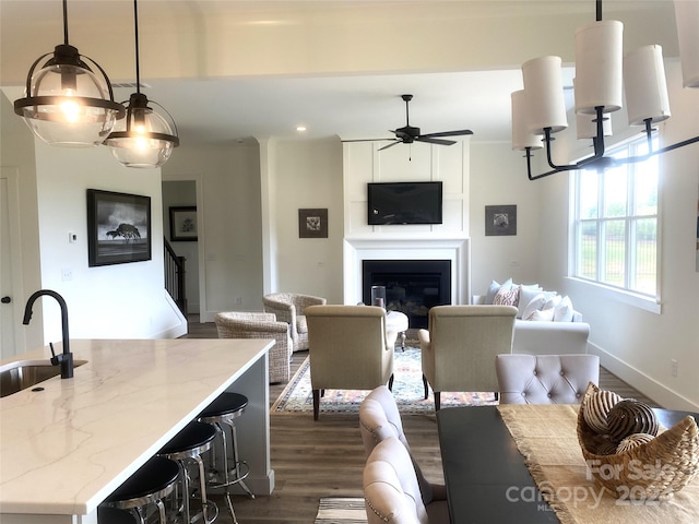 living room with ceiling fan with notable chandelier, sink, and dark wood-type flooring