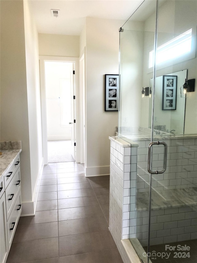 bathroom featuring tile patterned floors, vanity, and a shower with door