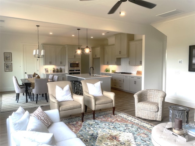 living room with sink, ceiling fan with notable chandelier, ornamental molding, and dark hardwood / wood-style floors