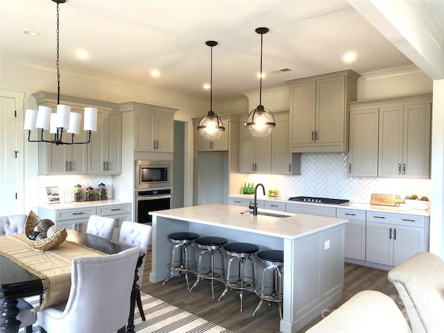 kitchen with pendant lighting, sink, a breakfast bar area, a kitchen island with sink, and stainless steel appliances