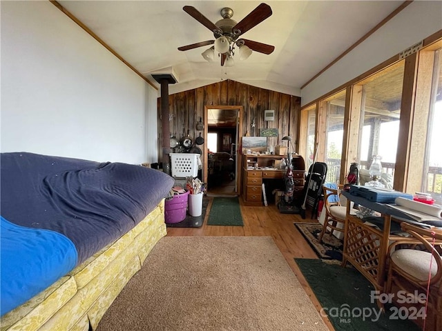 living room with wood walls, wood-type flooring, crown molding, ceiling fan, and lofted ceiling