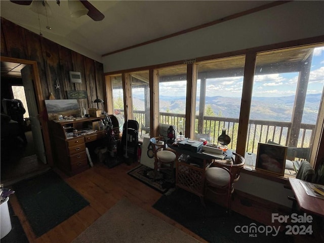 home office with a wealth of natural light, hardwood / wood-style floors, ceiling fan, and wooden walls