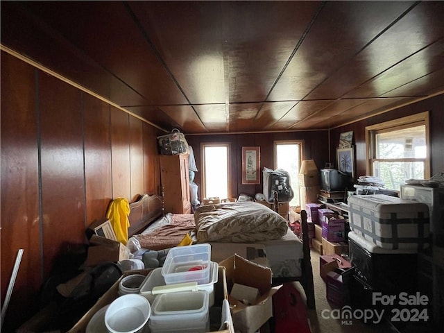 bedroom with multiple windows and wood walls