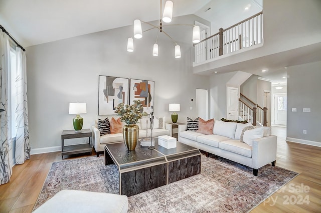 living room featuring a wealth of natural light, light hardwood / wood-style floors, a high ceiling, and a chandelier