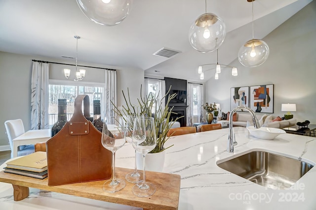 interior space featuring decorative light fixtures, sink, a notable chandelier, and light stone countertops